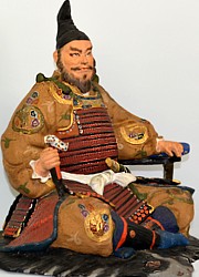 japanese clay doll of a shogun sitting on bearskin rug